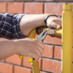 Closeup photo of male engineer fixing pressure valve on yellow pipes