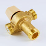 Water various supply plumbing brass thermostatic mixing valve isolated on white background.