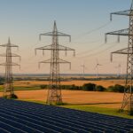 Stromversorgung in Deutschland: Erzeugung, Netze und Markt Hochspannungsmasten in einer Landschaft mit Windrädern am Horizont und einem Solarpark im Vordergrund